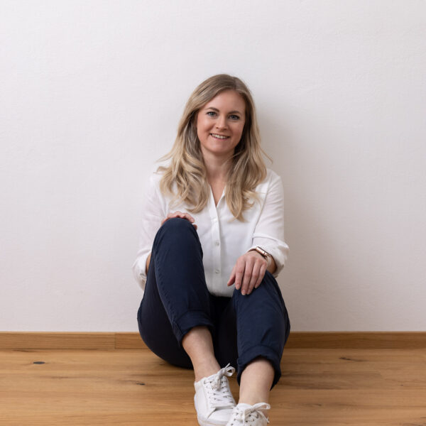 Miriam Thon ValueUp Portrait, sitzt am Boden an der Wand, positive Ausstrahlung