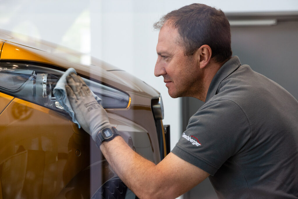 Mitarbeiter poliert die Scheinwerfer des Autos