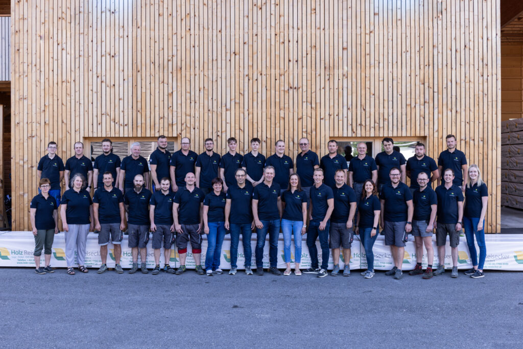 Teambild Holz Reisecker vor Holzfassade