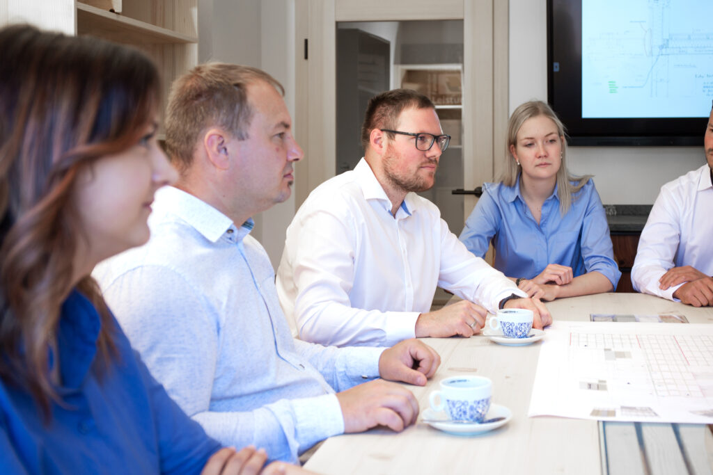 Besprechung mit mehreren Personen am Tisch, Holzbau Plan am Tisch