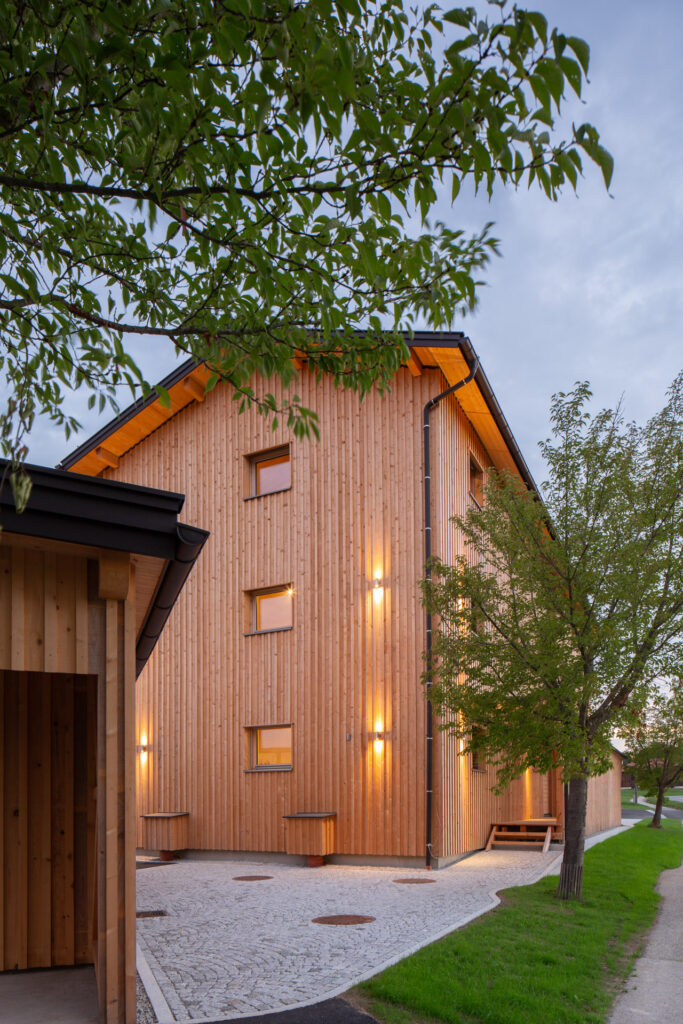 Ansicht des Holz Wohnbaus in der Dämmerung mit Fassadenbeleuchtung