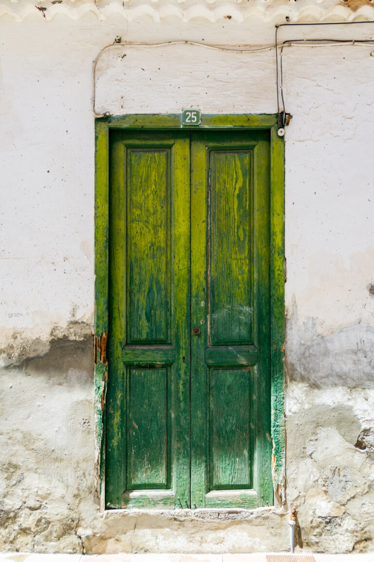 La Gomera kaputte Wand weiße Dachlamellen gelbgrüne-dunkelgrüne alte Holztüre, die schon mehrere bröckelige Schichten freilegt