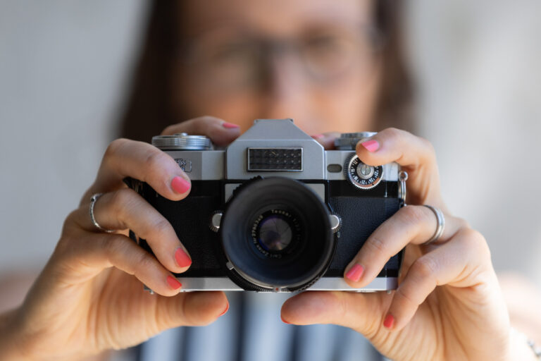 Kamera im Fokus, neonfarbene Nägel, Brigitte verschwommen im Hintergrund