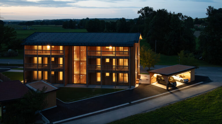 Drohnenansicht in der Dämmerung des beleuchteten Holz Wohnbaus