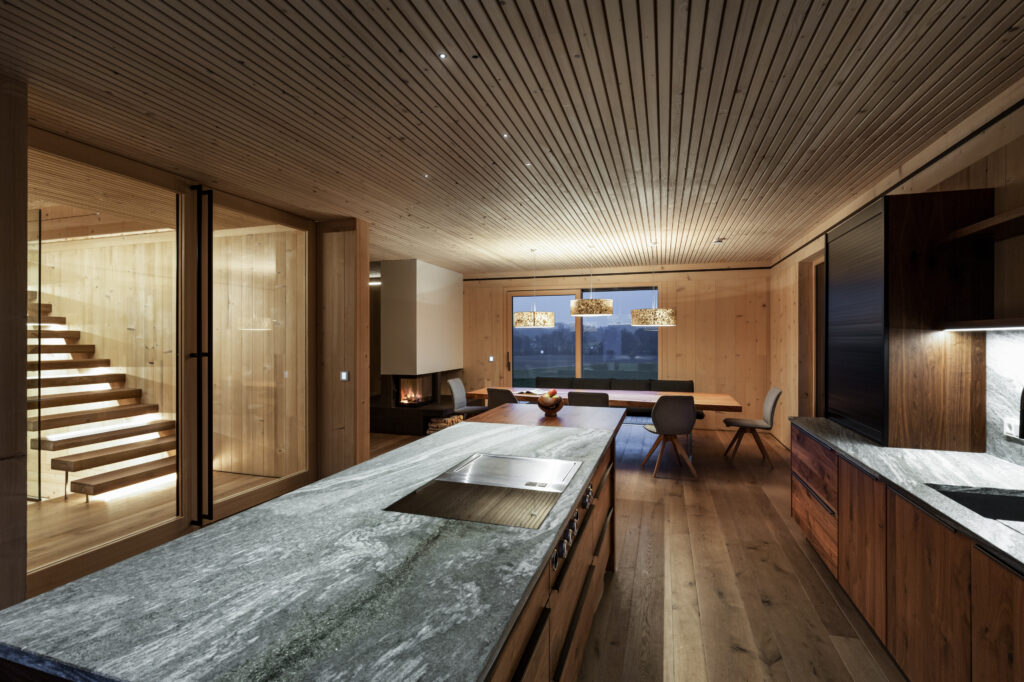 Küche im Wohnhaus in Holzbauweise mit Blick in Richtung Esszimmer und Kamin