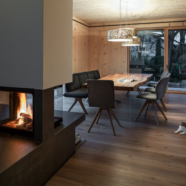 Wohnraum mit Kaminfeuer, Blick in Richtung Esszimmer. Katze liegt am Boden.