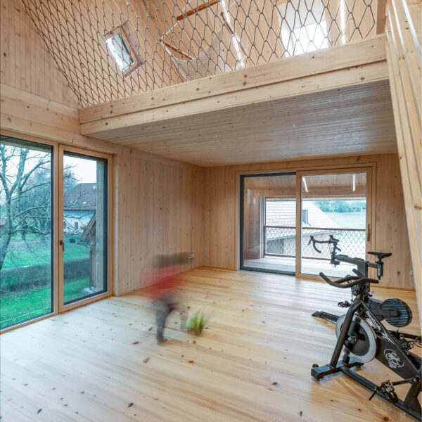 Fitnessraum in Holzbau Projekt mit spielendem Kind verschwommen sichtbar